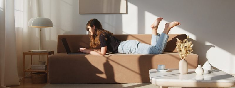 A woman reclines on a couch with her legs raised, relaxing in a cozy living space.