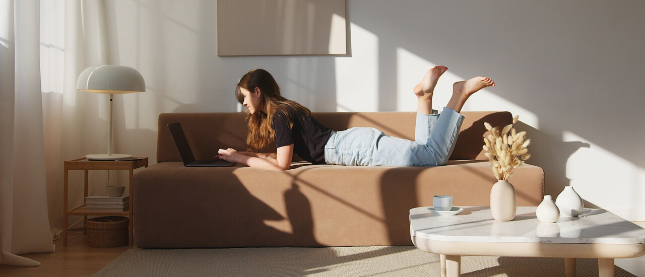 A woman reclines on a couch with her legs raised, relaxing in a cozy living space.