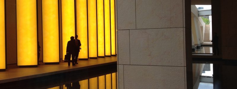 A person walks through a modern hallway illuminated by warm yellow lights, showcasing contemporary architectural design.