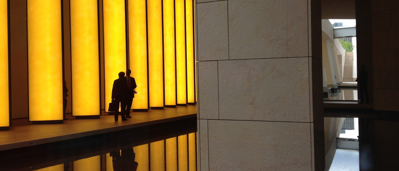 A person walks through a modern hallway illuminated by warm yellow lights, showcasing contemporary architectural design.