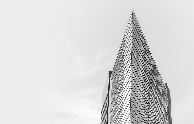 Black and white photo of a tall building, showcasing its architectural details against a clear sky.
