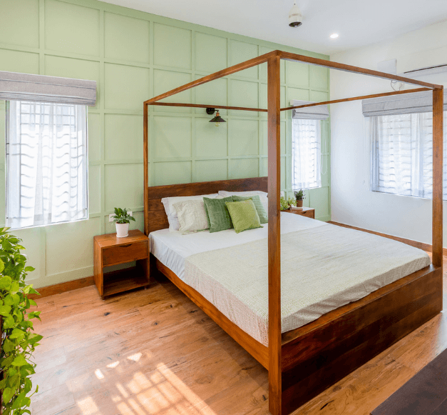 A cozy bedroom featuring a canopy bed against vibrant green walls, creating a serene and inviting atmosphere.