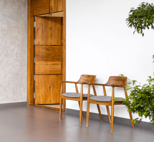 Two chairs positioned beside a door, creating a cozy seating area in a well-lit space.