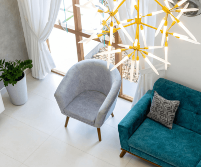 A cozy living room featuring a blue couch and an elegant gold chandelier hanging from the ceiling.