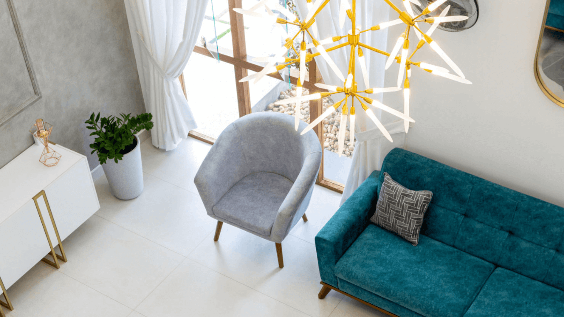 A cozy living room featuring a blue couch and an elegant gold chandelier hanging from the ceiling.